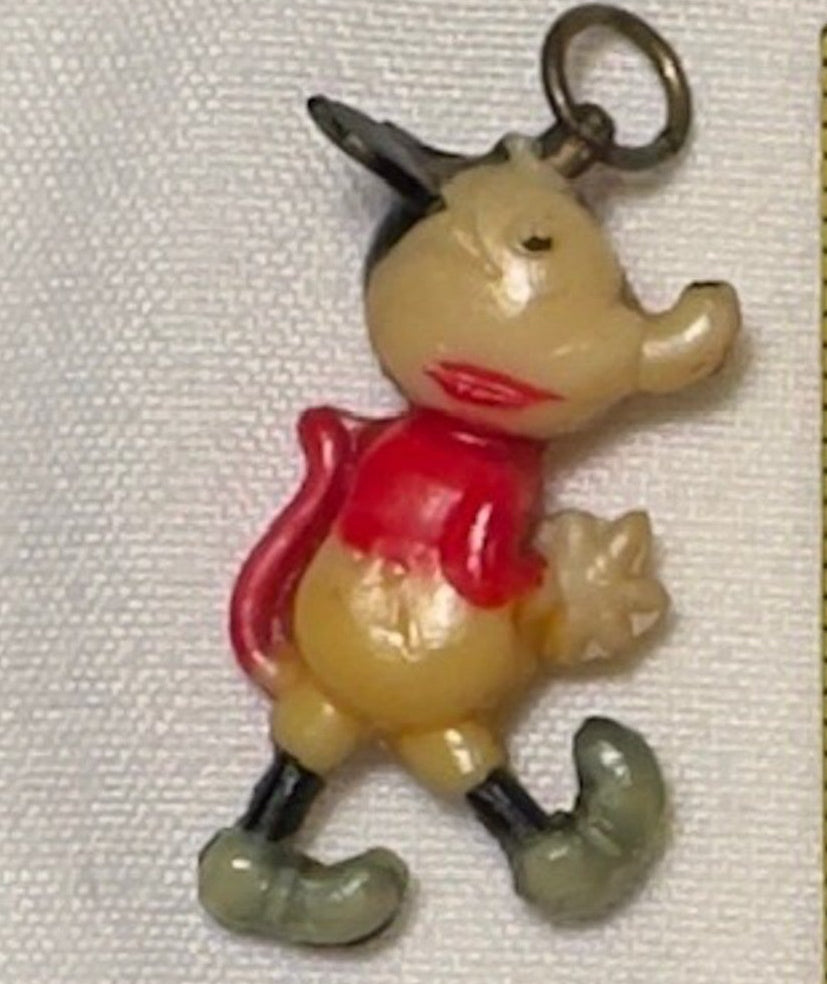 Small cartoon character charm next to a ruler on a white background