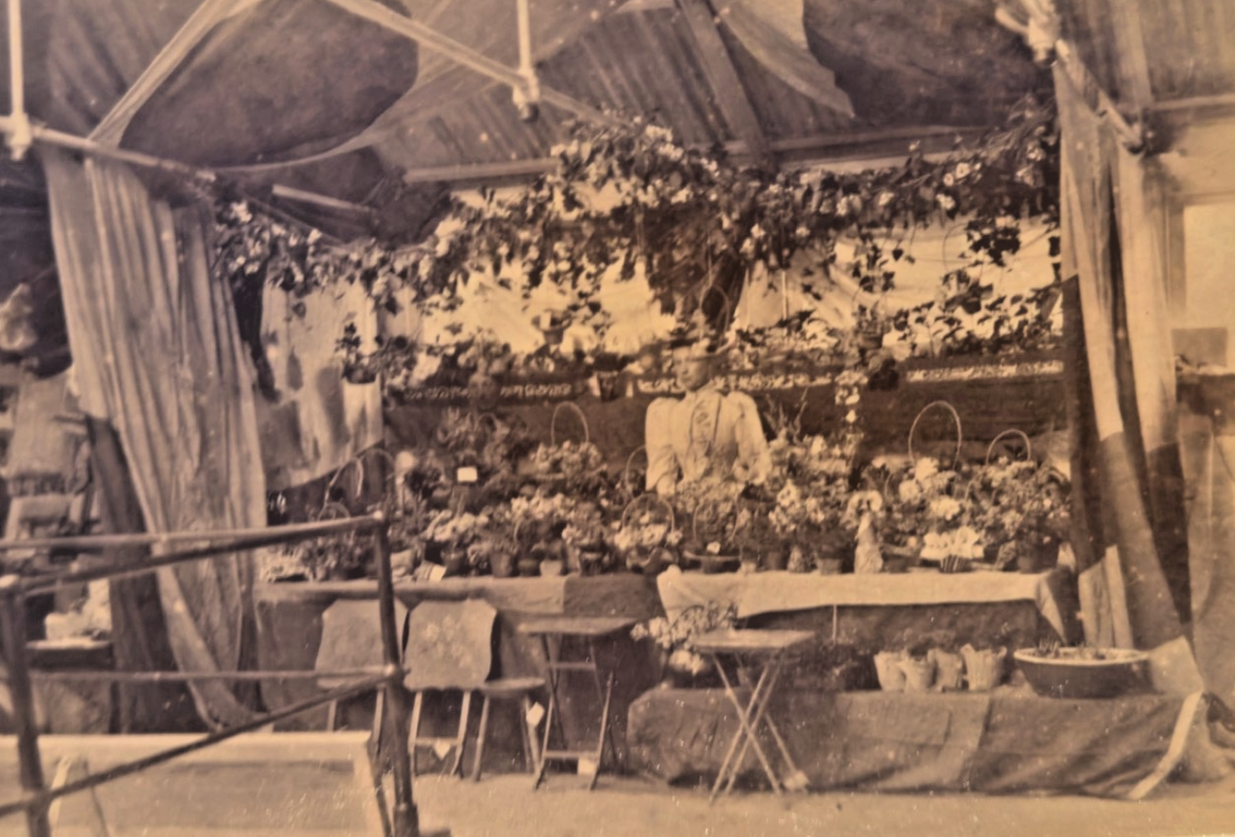 Vintage black and white photo of a floral display inside a tent.
