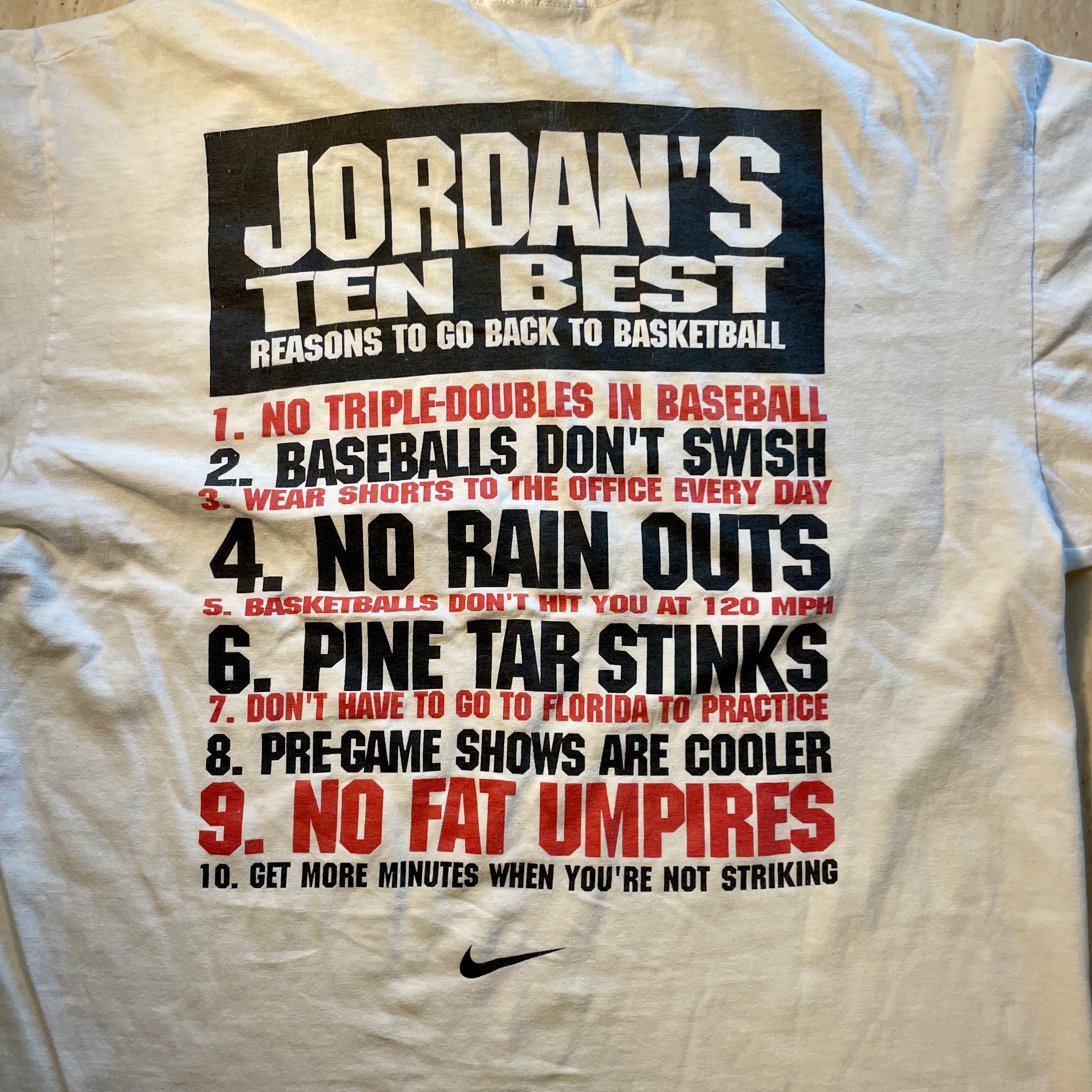 White t-shirt with humorous text about reasons to go back to basketball, featuring a Nike logo.