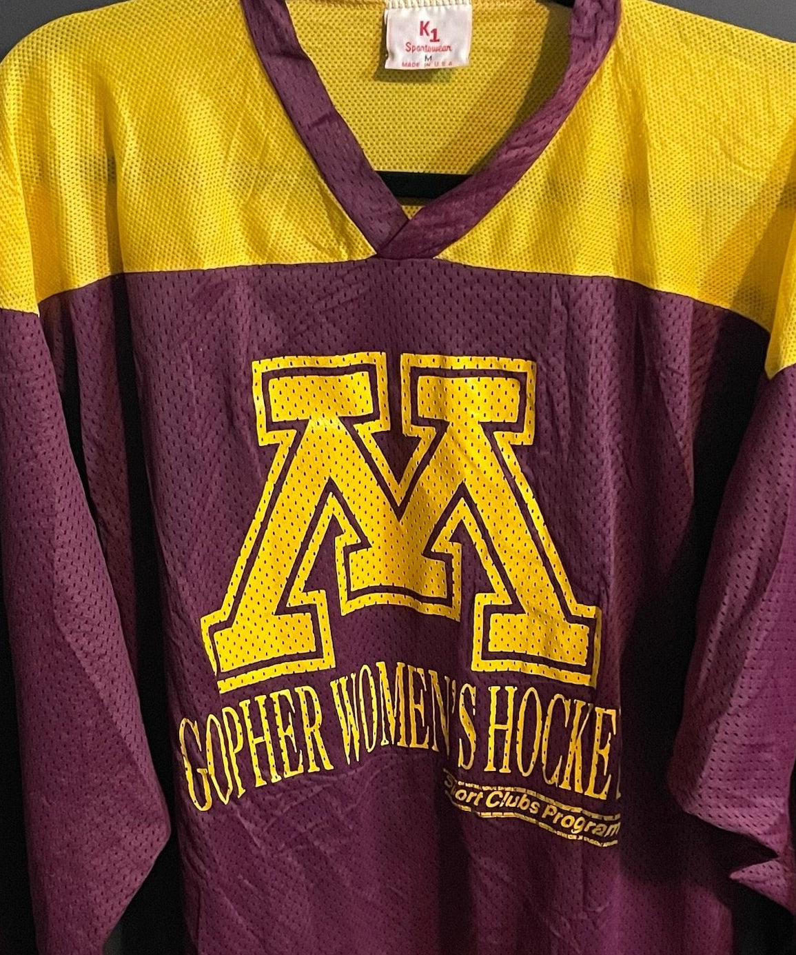 Maroon and yellow hockey jersey with 'Gopher Women's Hockey' text on a dark background