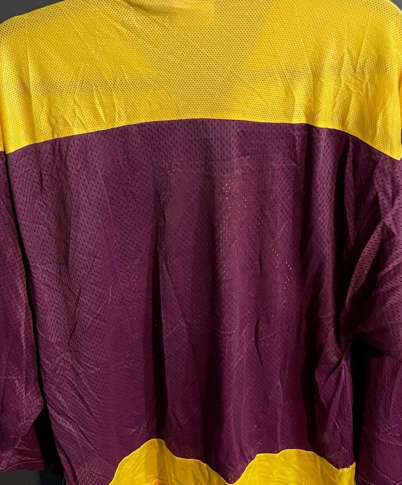 Purple and yellow sports jersey hanging on a dark gray wall.