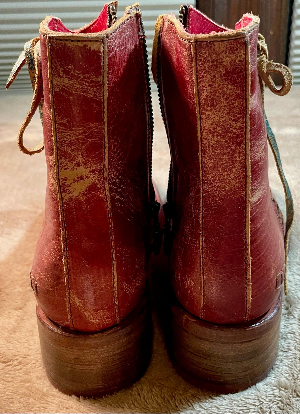 Pair of red leather boots on a textured surface