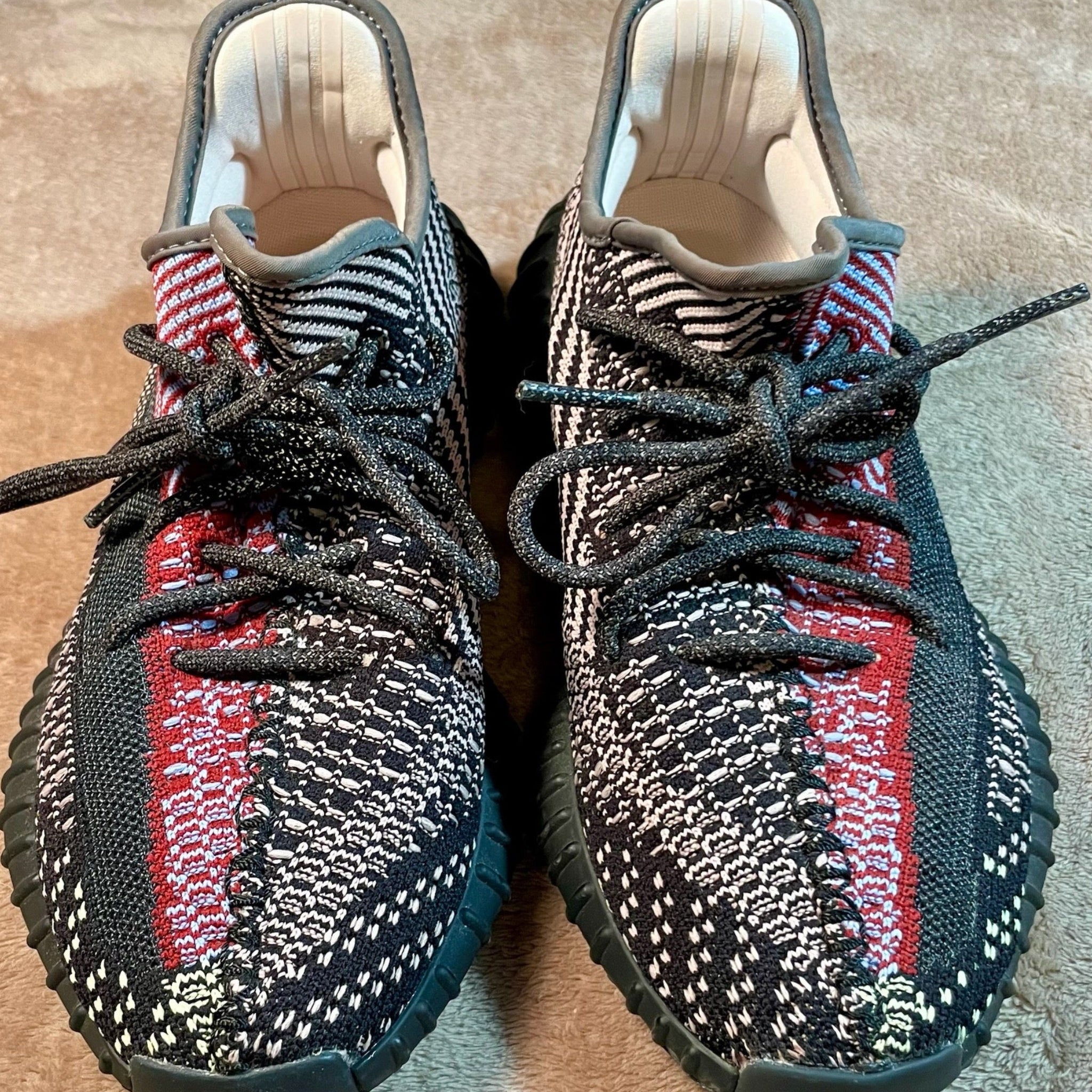 Pair of black, red, and white patterned sneakers on a textured surface