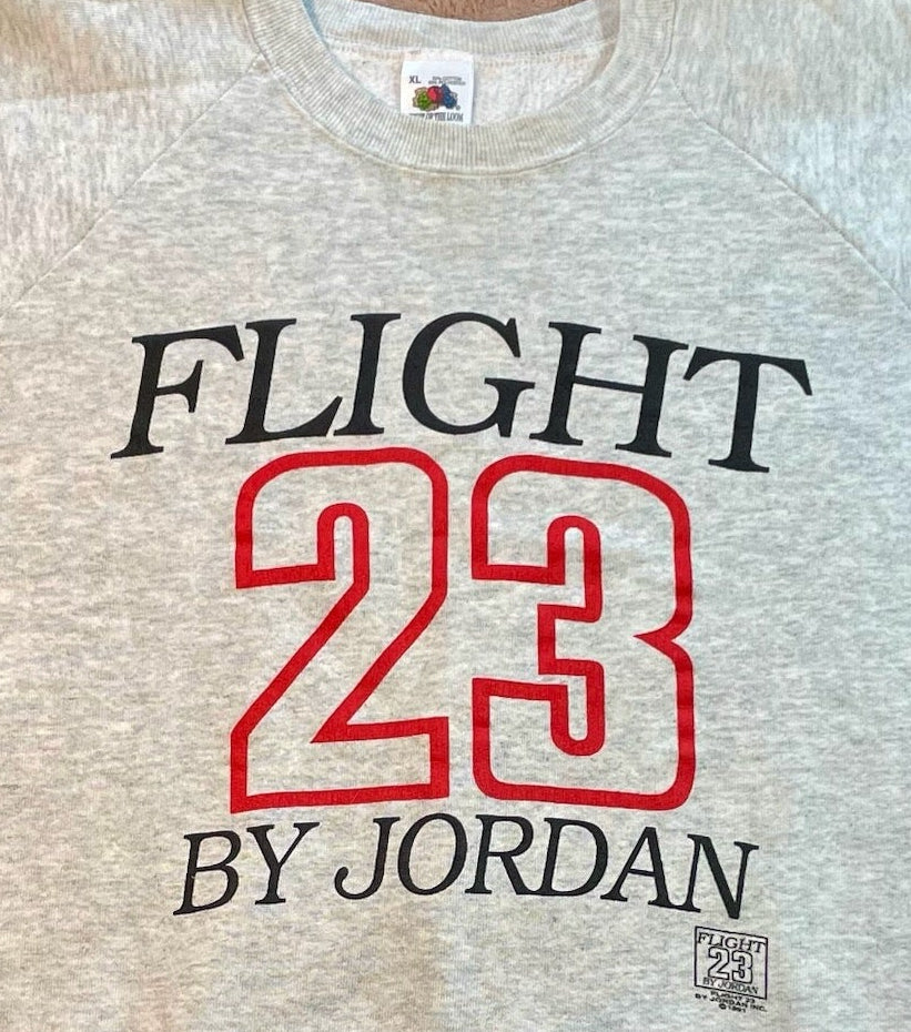 Beige sweatshirt with 'FLIGHT 23 BY JORDAN' text on a wooden surface