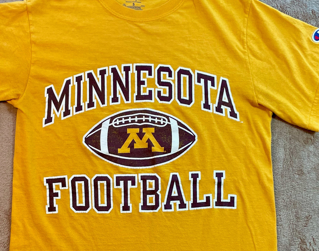 Yellow t-shirt with 'Minnesota Football' text and logo on a textured surface