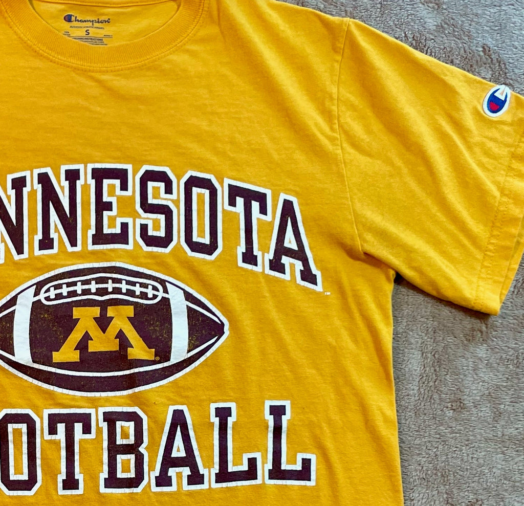Yellow t-shirt with 'Minnesota Football' text and logo on a textured surface