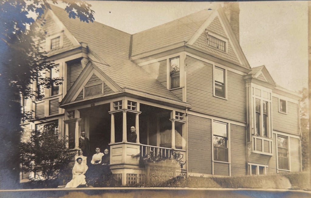 Vintage photograph of a family on a porch in front of a large house