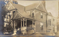 Vintage photograph of a family on a porch in front of a large house