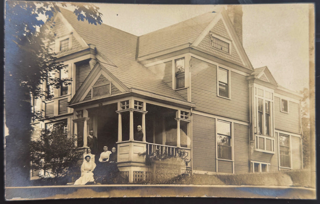 Vintage photograph of a family on a porch in front of a large house