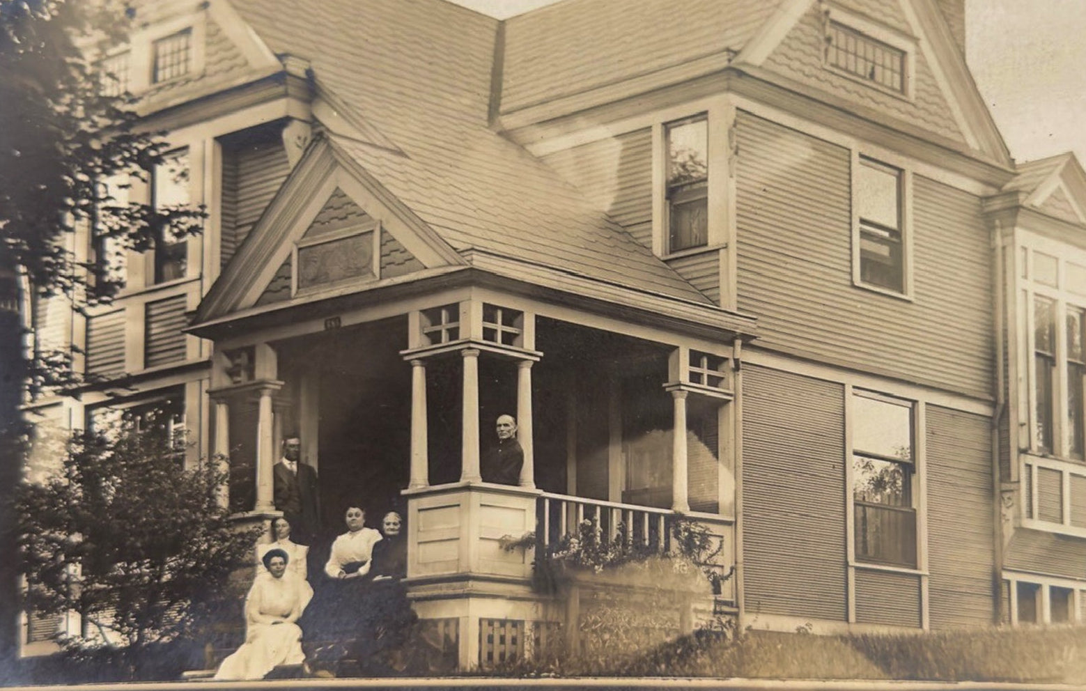 Vintage photograph of a family on a porch in front of a large house