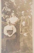 Vintage sepia-toned photograph of a family outdoors with trees in the background