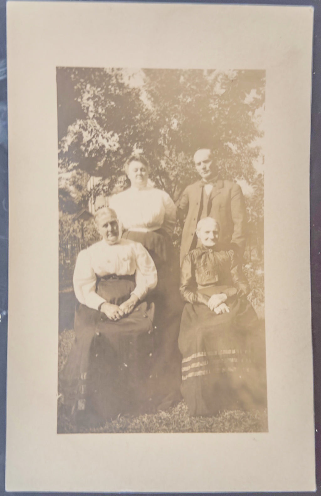Vintage sepia-toned photograph of a family outdoors with trees in the background