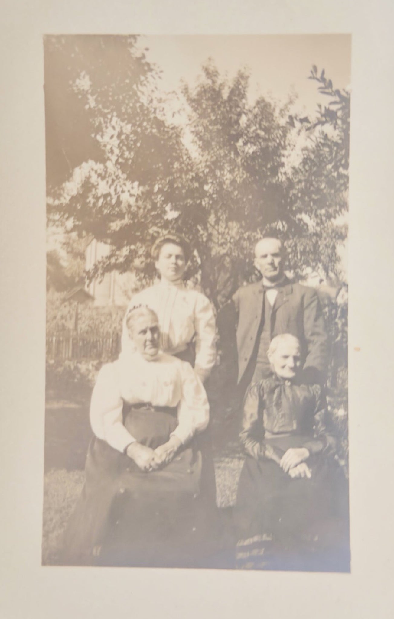 Vintage family portrait of four people outdoors with trees in the background