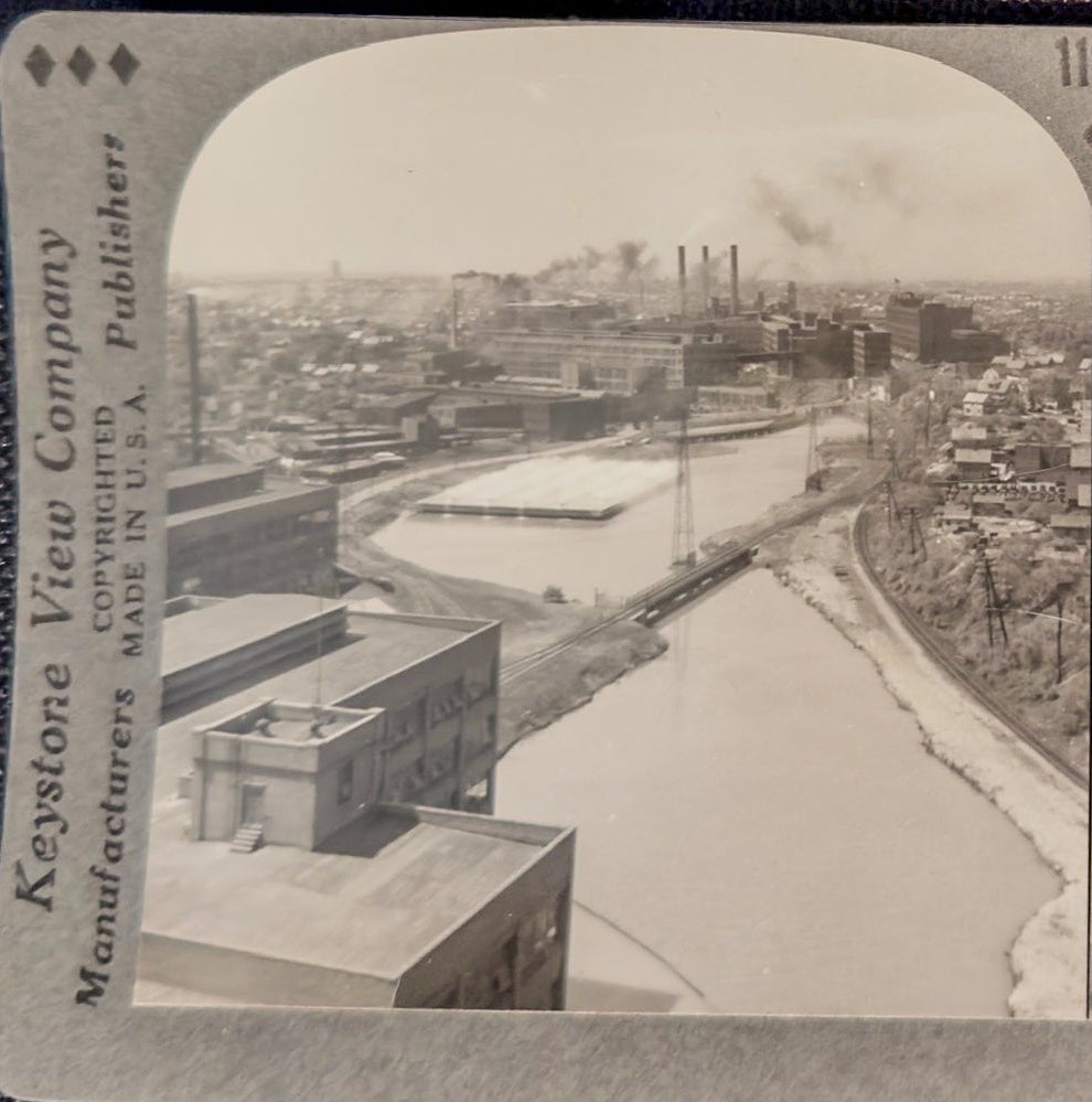 Stereoscopic view of a cityscape with buildings and a river, featuring Keystone View Company branding.