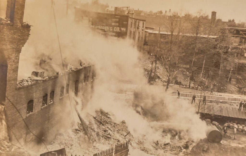 A sepia-toned photograph of a destroyed urban area with smoke billowing from buildings.