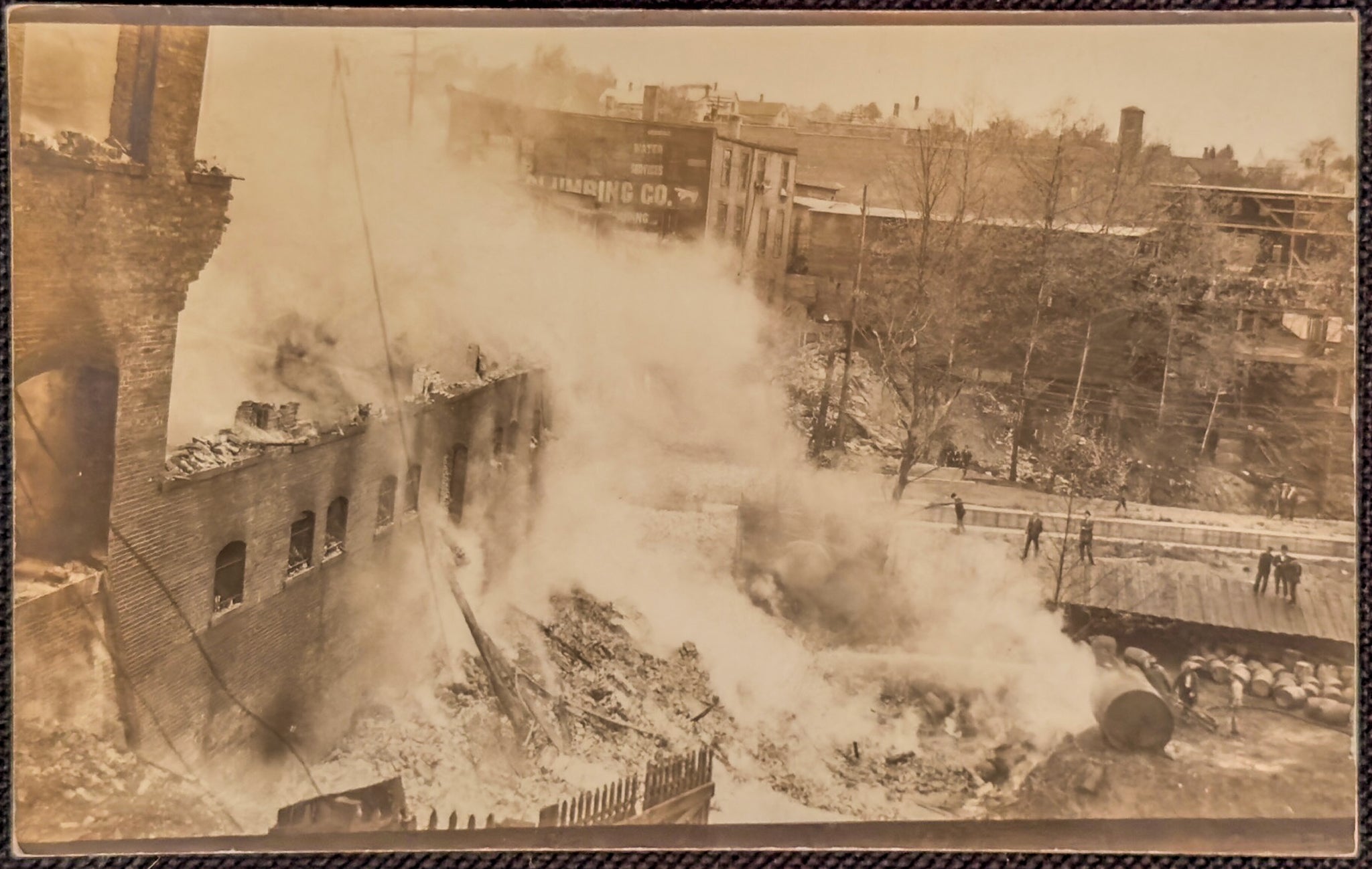 A sepia-toned photograph of a destroyed urban area with smoke billowing from buildings.