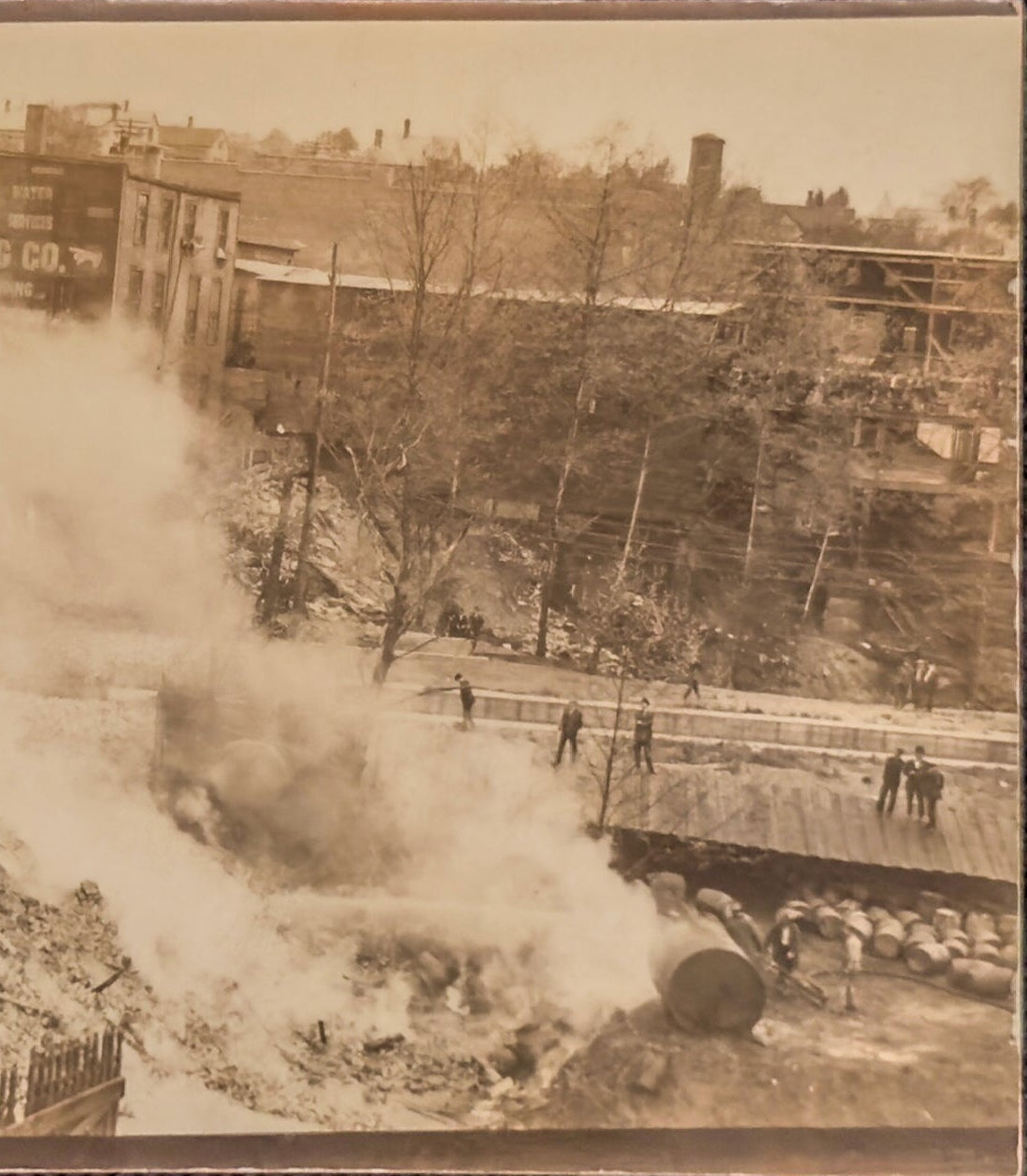 A sepia-toned photograph of a destroyed urban area with smoke billowing from buildings.