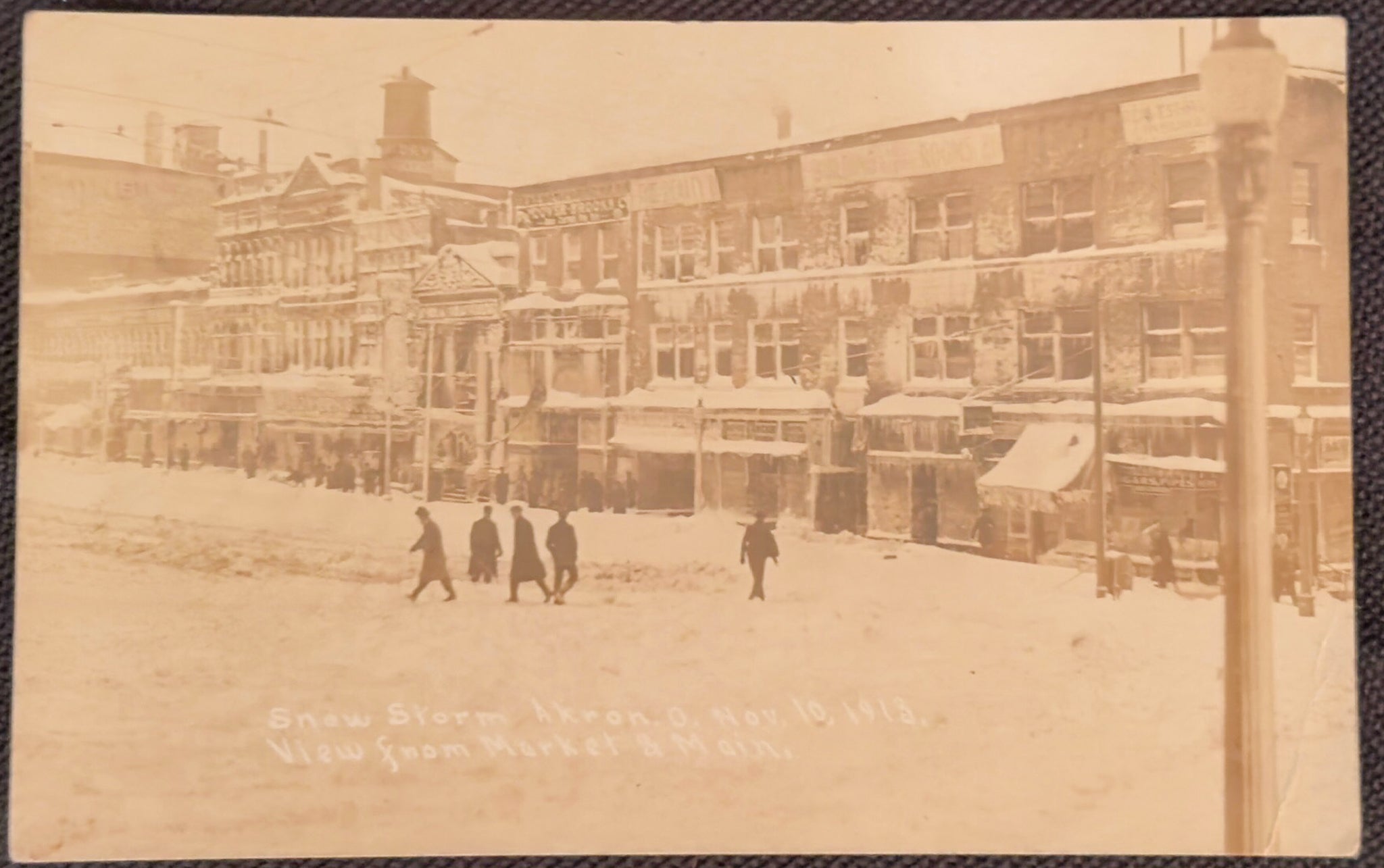 Vintage sepia-toned photograph of a snowy street scene with people and buildings.