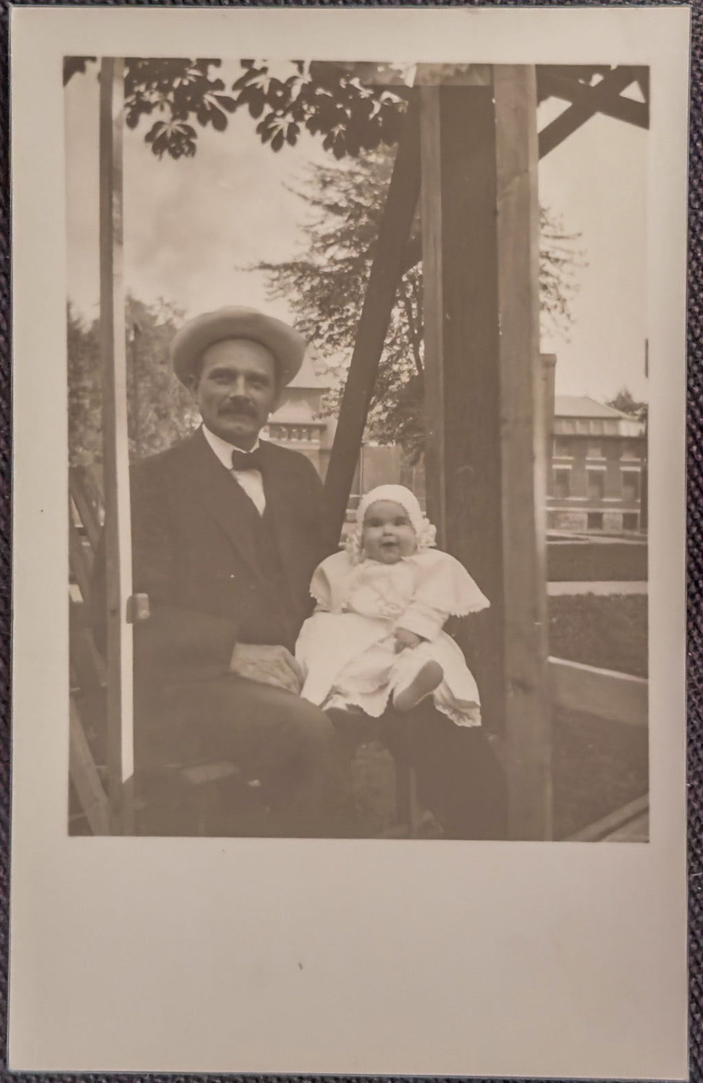 Vintage black and white photo of a man and a baby sitting together outdoors.