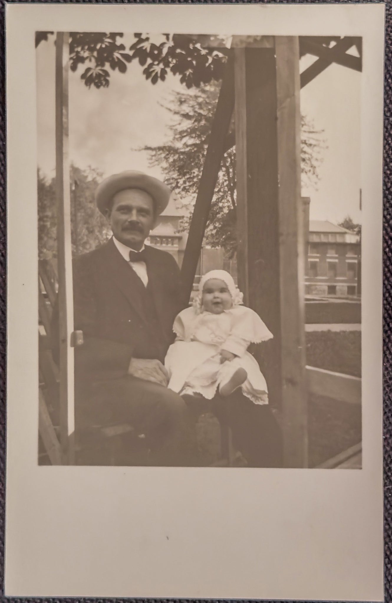 Vintage black and white photo of a man and a baby sitting together outdoors.