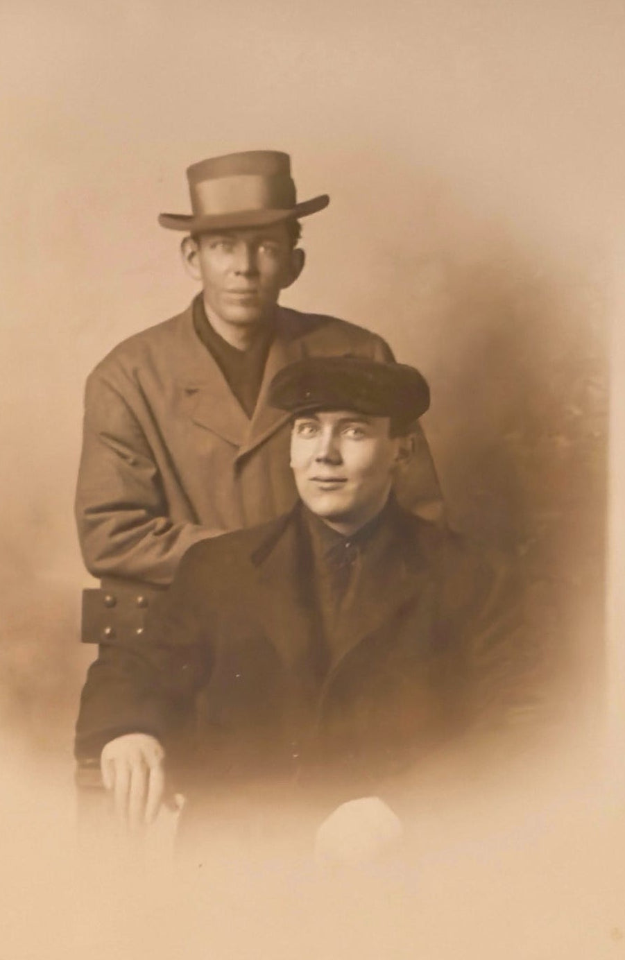 Vintage sepia-toned photograph of two men wearing hats and coats.