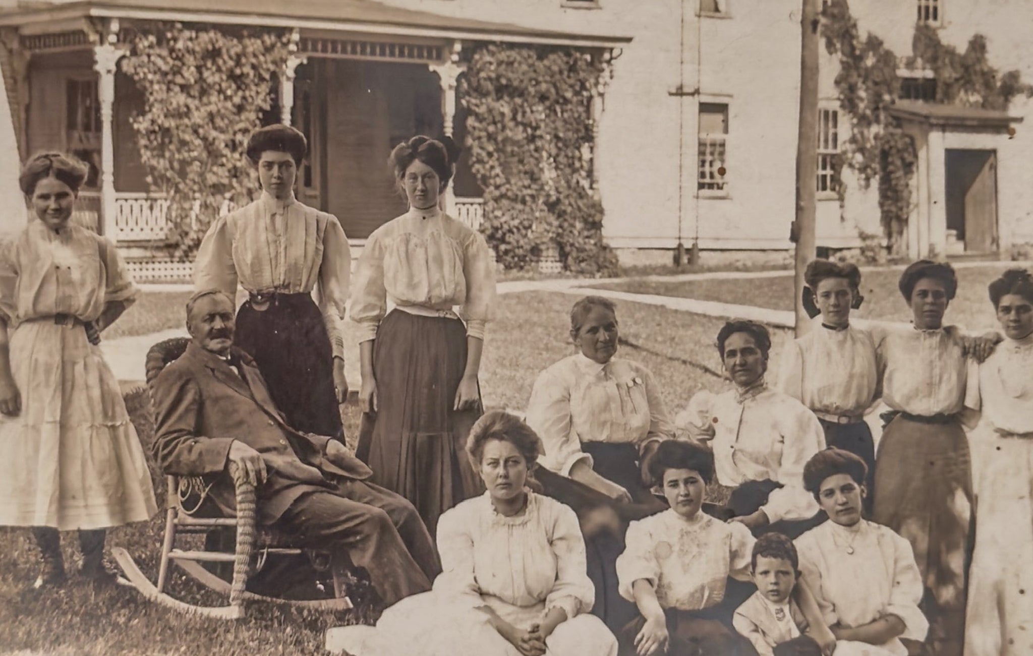 Vintage photograph of a group of people in front of a house with decorative elements.