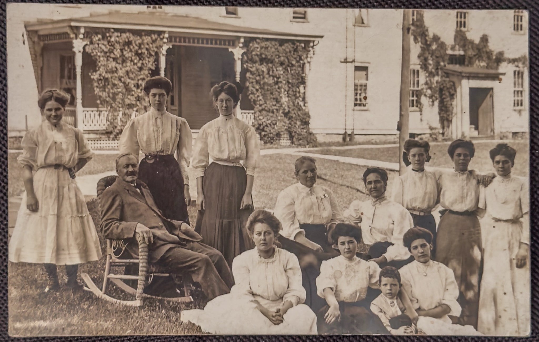 Vintage photograph of a group of people in front of a house with decorative elements.
