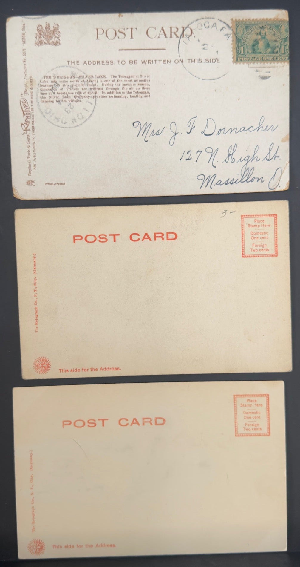 Three vintage postcards in a display case on a dark surface