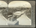 Vintage stereo card of a cityscape with a river and industrial buildings, featuring text on the edges.