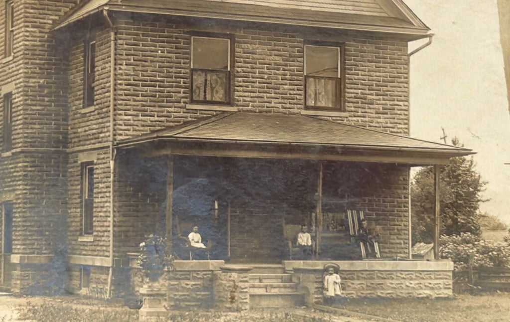 Vintage black and white photo of a two-story house with a porch