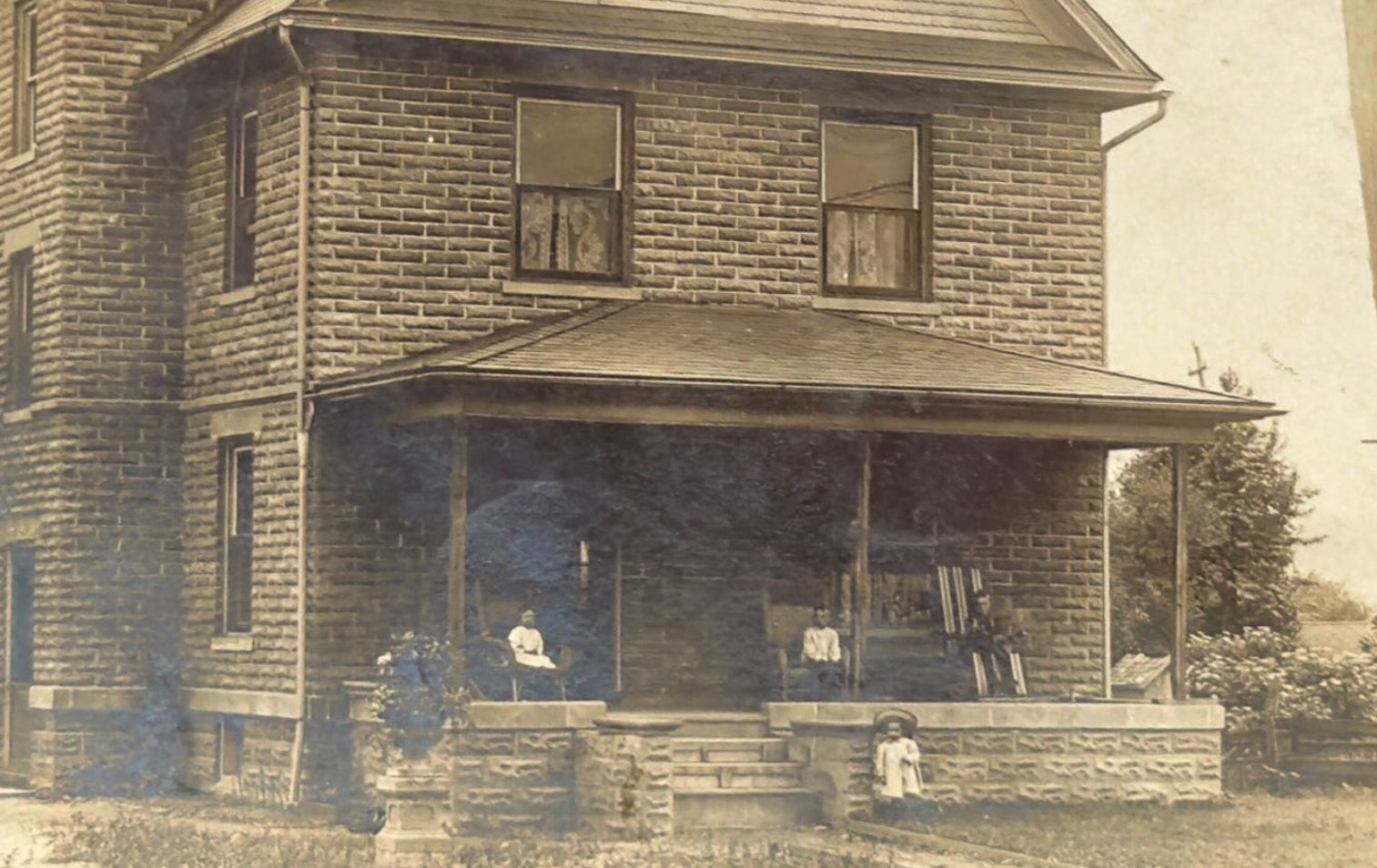 Vintage black and white photo of a two-story house with a porch