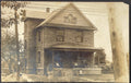 Vintage black and white photo of a two-story house with a porch