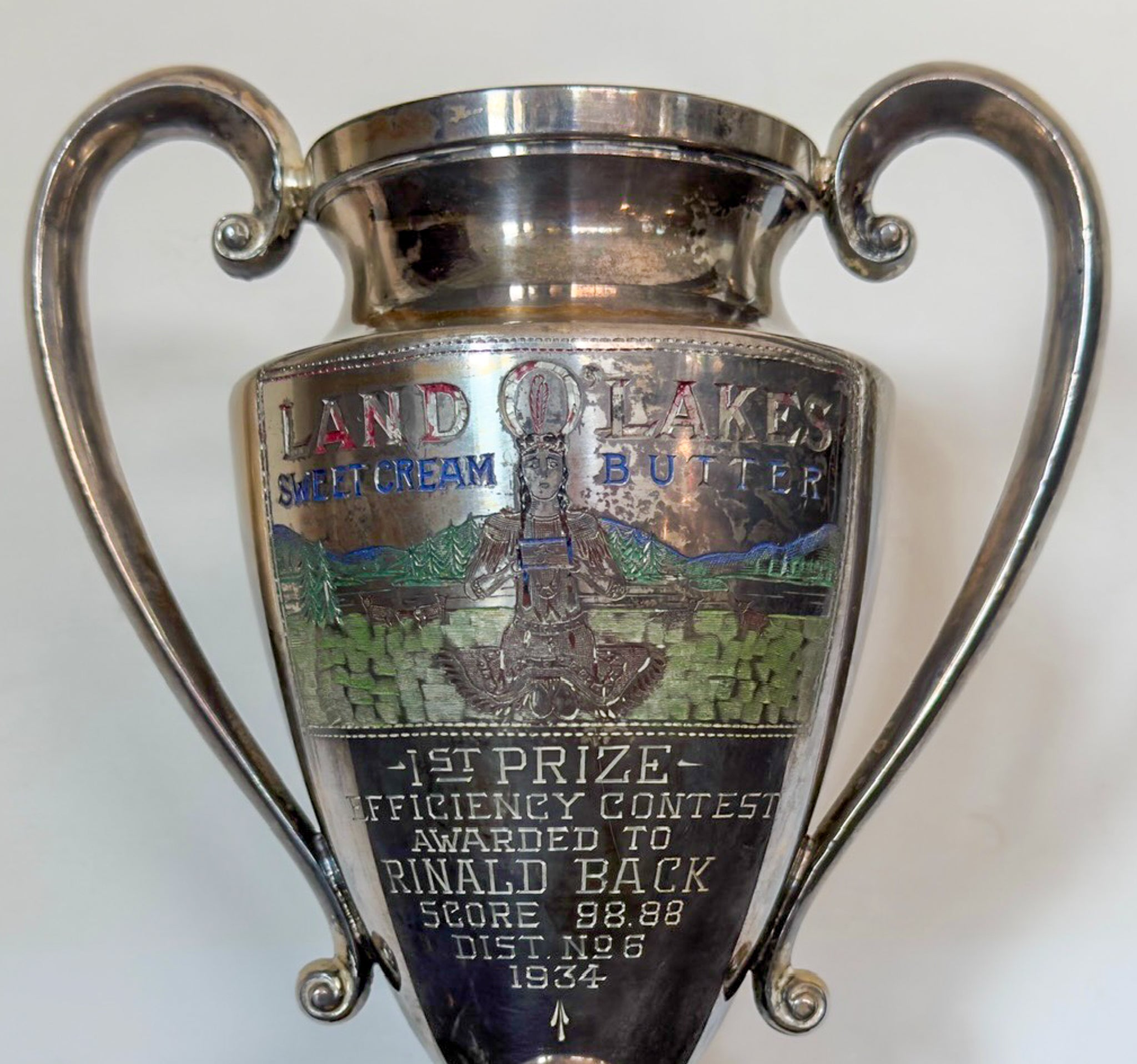 Silver trophy with engraved text and branding on a white background