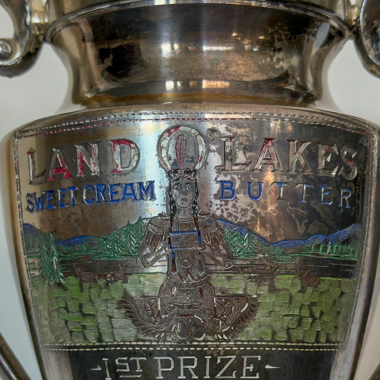 Silver trophy with engraved text and a scenic design on a white background