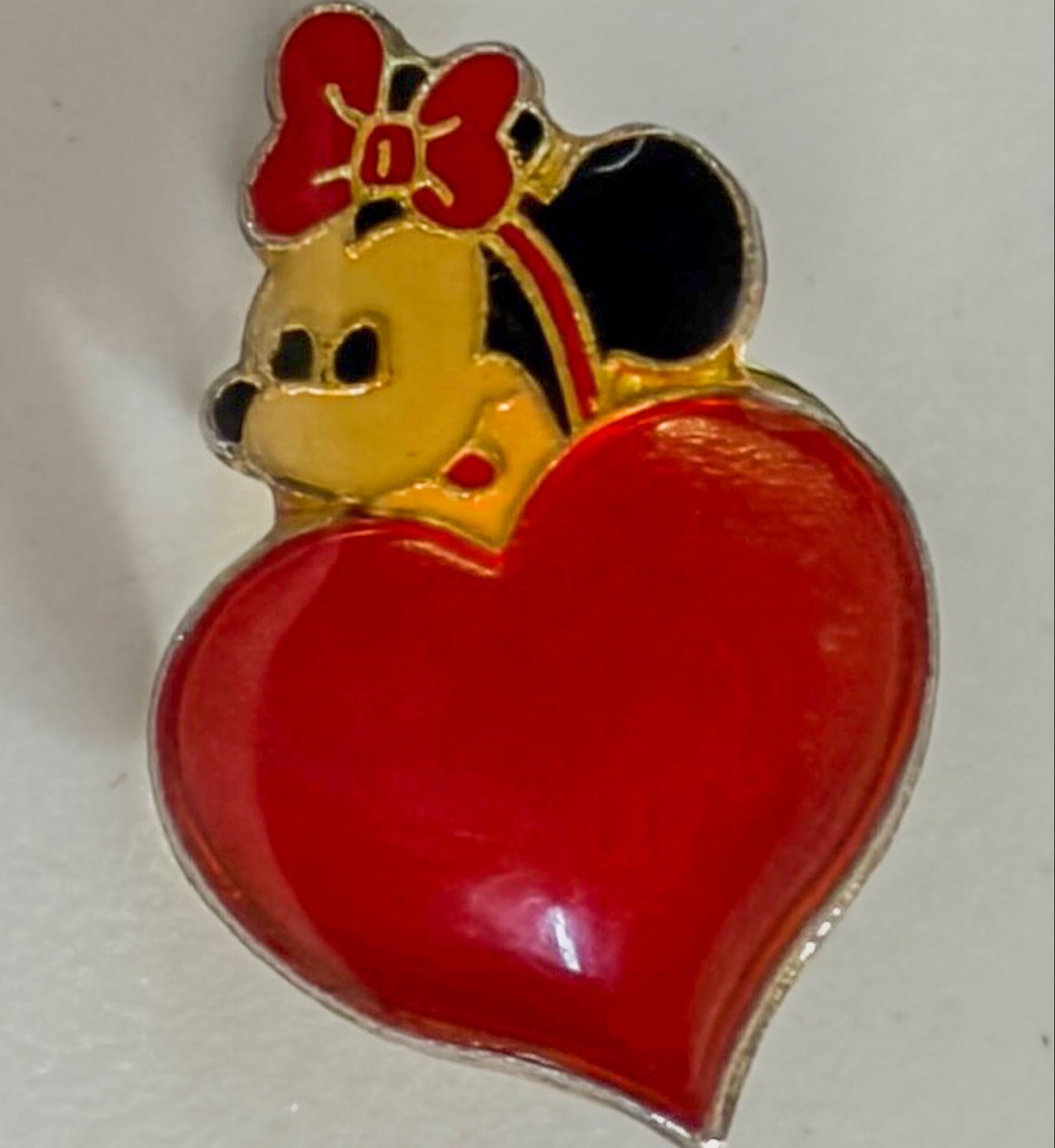Pin with cartoon character holding a red heart on a white background