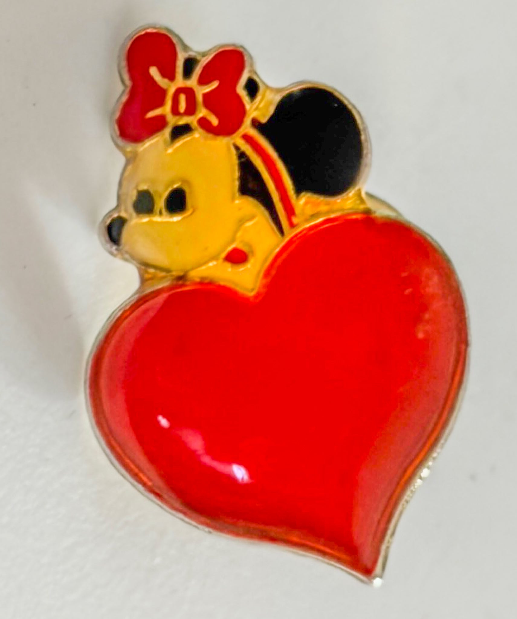 Pin with a character in a red dress and bow on a heart-shaped background