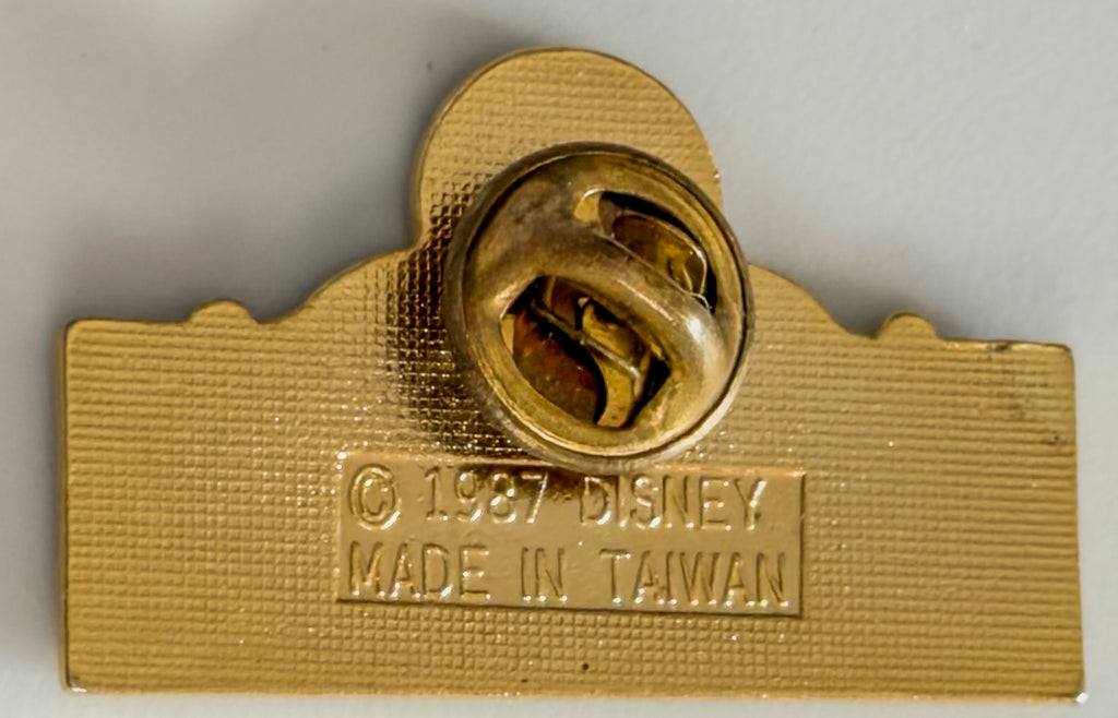 Gold Disney pin with 'Made in Taiwan' text on a gray background