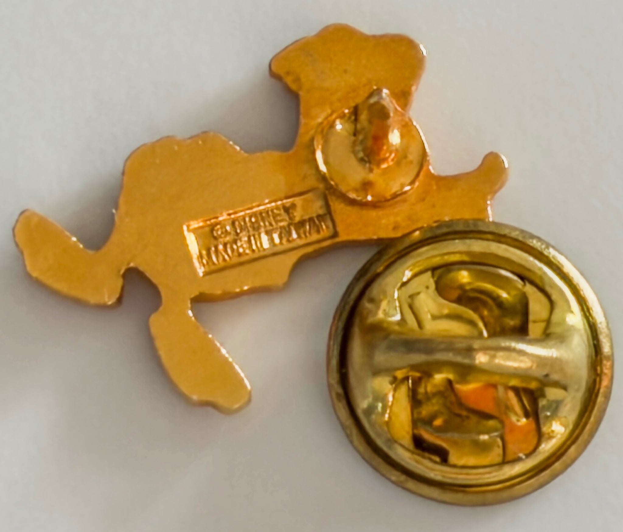 Gold-colored badge with a central emblem on a white background