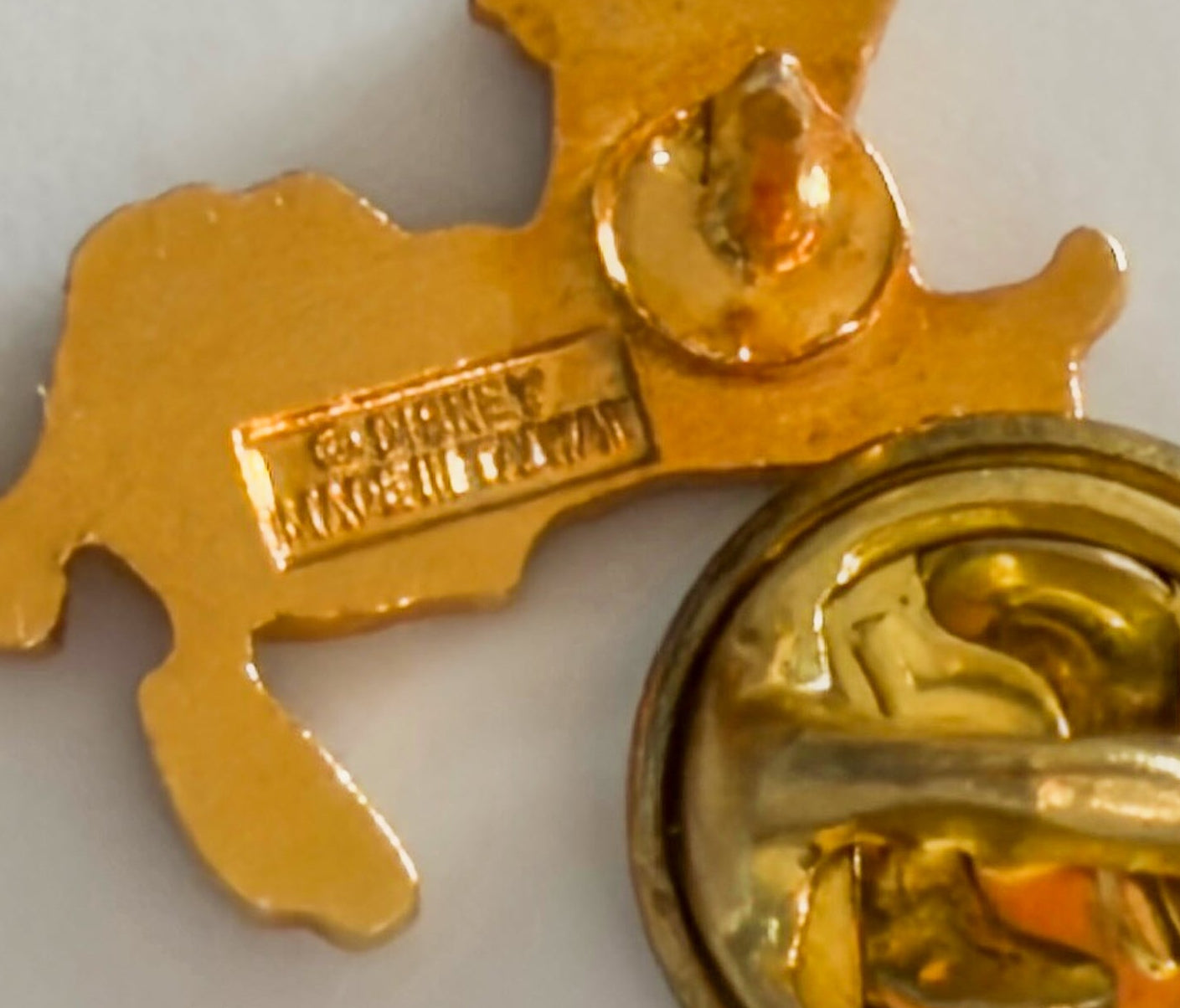 Gold-colored badge with a central emblem on a white background