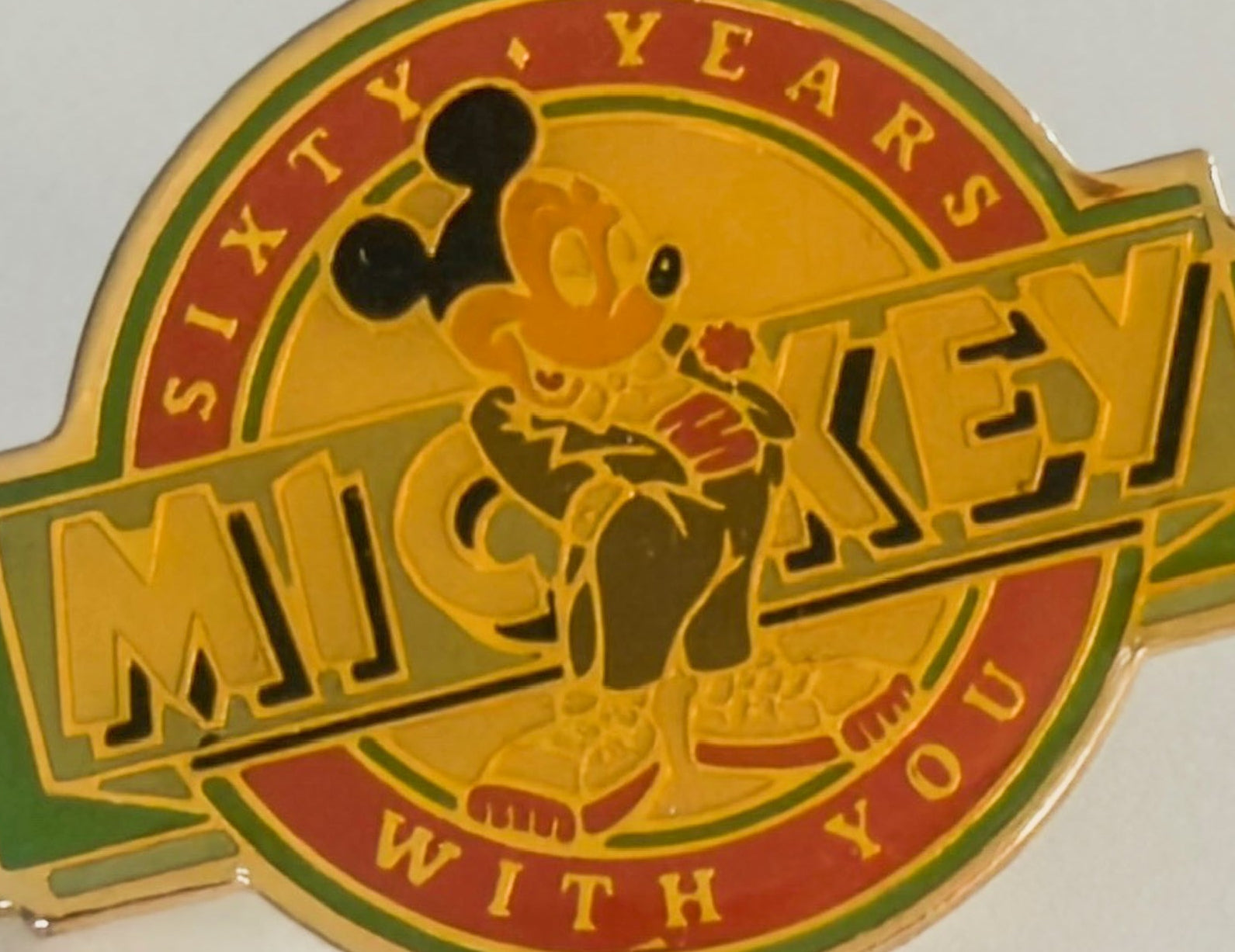 Mickey Mouse pin celebrating 60 years with text on a white background