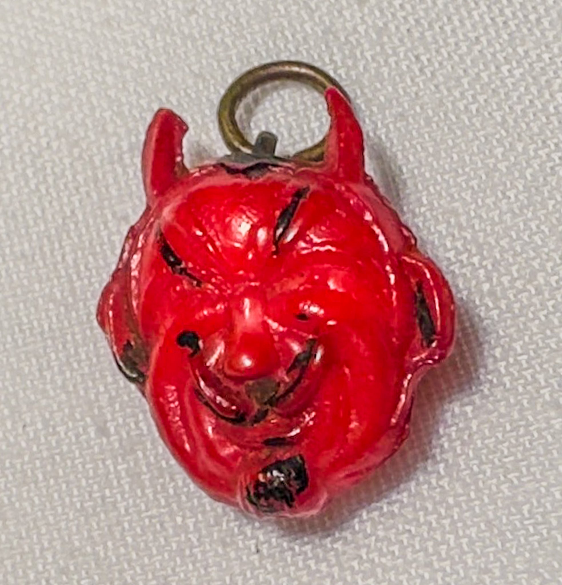 Red devil head charm on a white background