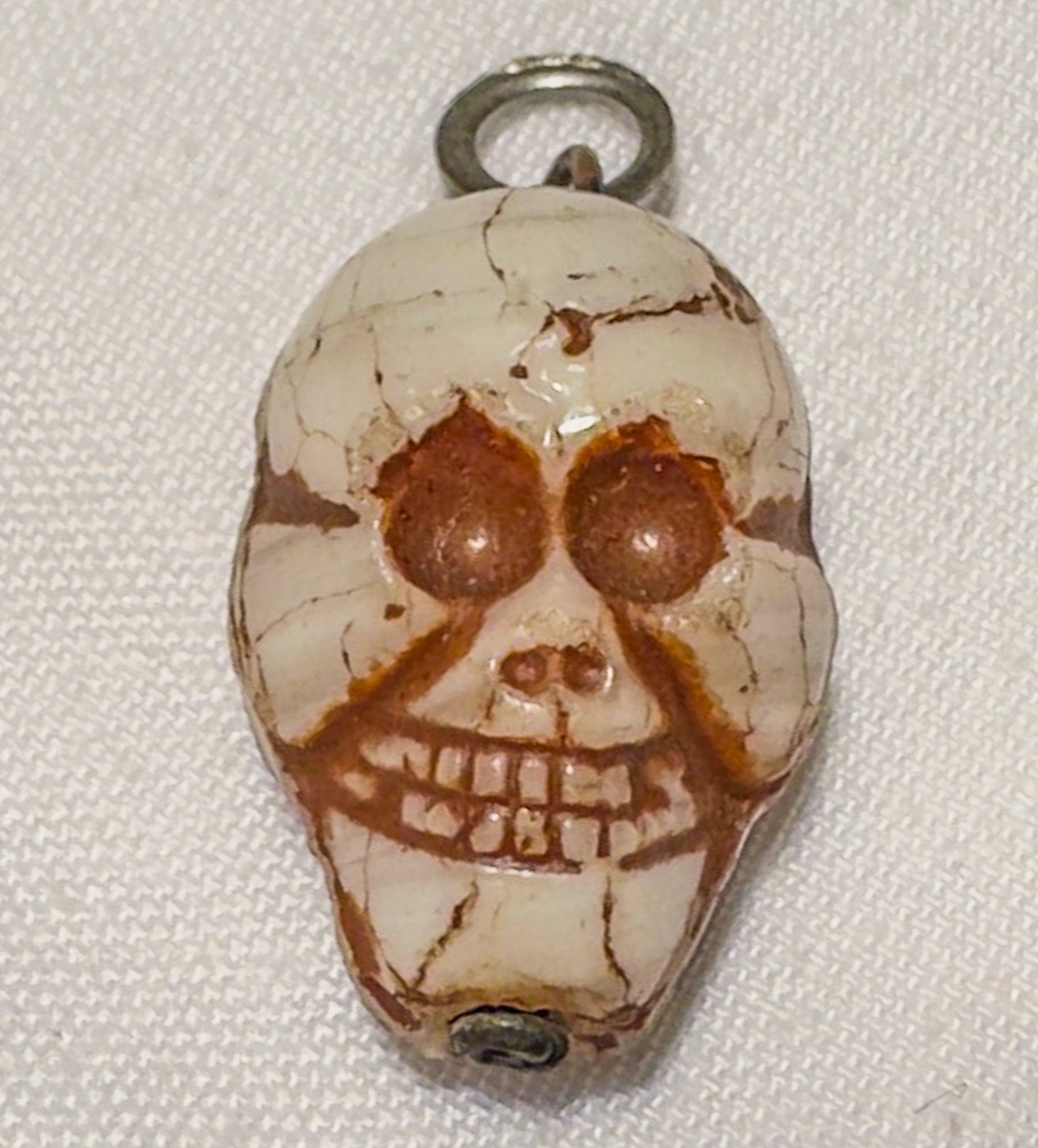 Skull-shaped stone pendant on a white background